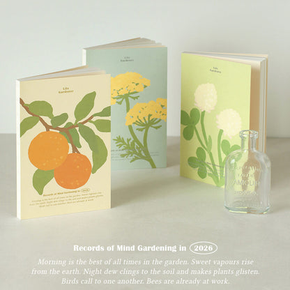 Three books with floral designs and a small bottle on a light surface.