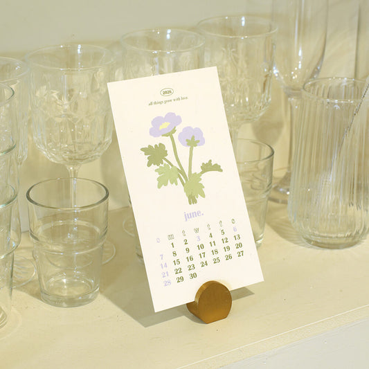 Calendar with purple floral design on a stand among clear glasses