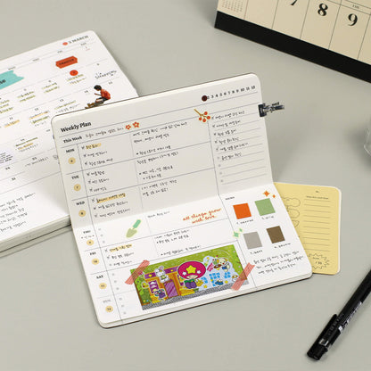 Planner with weekly schedule and colorful stickers on a gray surface with a pen and additional planner pages.