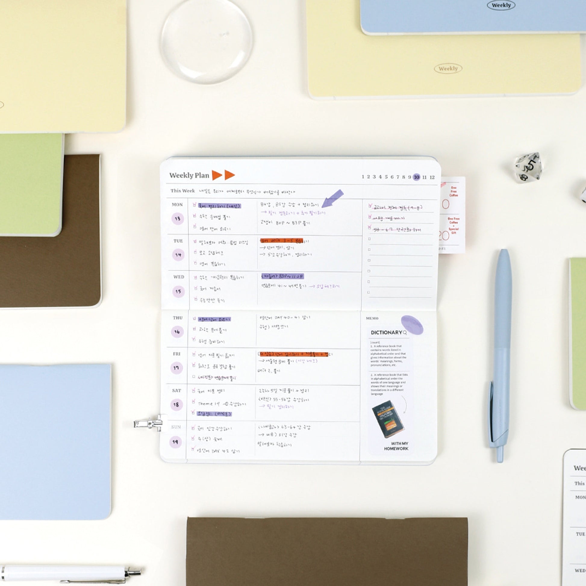 Physical weekly planner displayed on a desk with stationery items and highlight on the schedule.